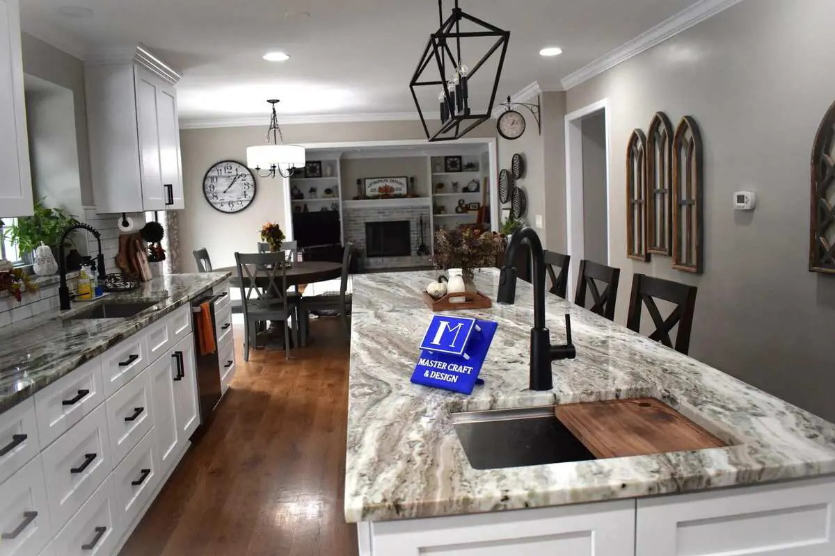 Completed open white kitchen with a stone island and warm wood floors